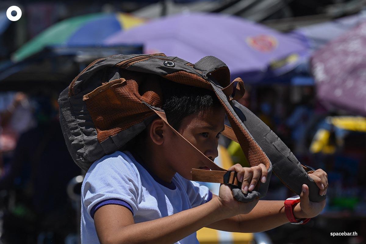 นักเรียนชายใช้กระเป๋าบังแดดในช่วงวันที่อากาศร้อนในกรุงมะนิลาเมื่อวันที่ 2 เมษายน 2024 (Photo by JAM STA ROSA / AFP) 