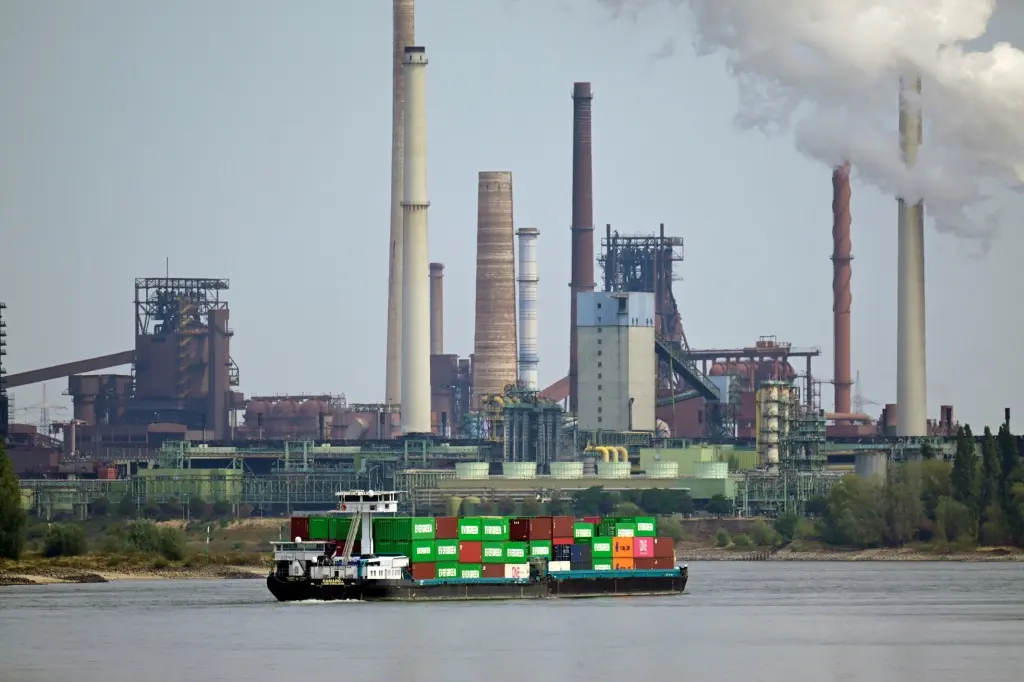 เรือบรรทุกตู้สินค้าลำหนึ่งแล่นผ่านบริษัท Thyssenkrupp Steel Europe AG ในเมืองดุยส์บวร์ก บนแม่น้ำไรน์