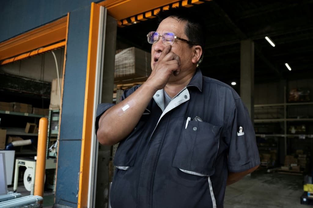 Konoe employee Isao Tabuchi wipes sweat from his eyes at the company's warehouse, a specialist wholesaler of screws and surveying equipment, on a hot day in Higashiosaka, Osaka Prefecture on August 21, 2026. The phonebooth-sized machine "Do Hiemon Box", where jets of ice-cold air ensure a temperature of 5C (41F), only launched this year but has proved popular in a country seemingly getting inexorably warmer.