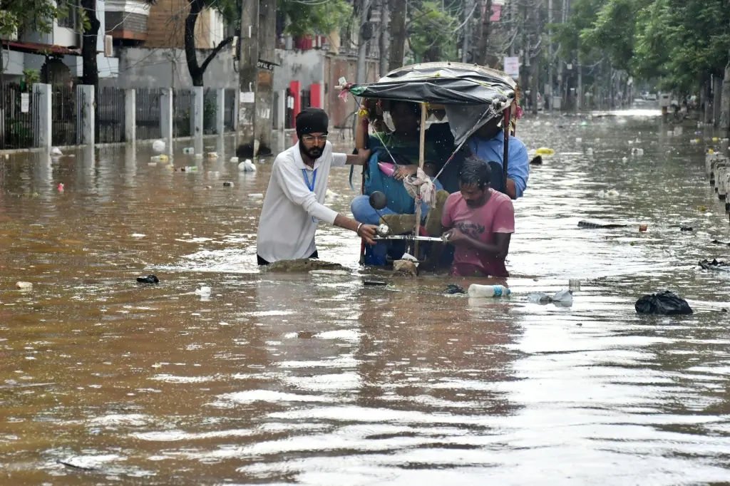 Residents wade through a flooded street following heavy monsoon rains in Guwahati on August 4, 2026