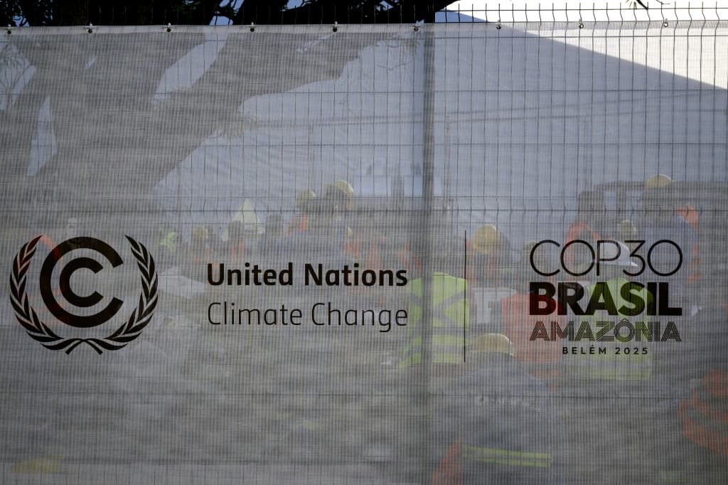 Workers rest behind a fence bearing the COP30 logo at a construction site in the City Park of the COP30, the United Nations Climate Change Conference in Belem, Para State, Brazil on November 3, 2025