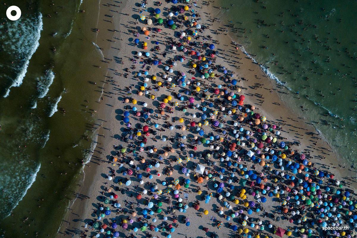 ภาพถ่ายมุมสูงเผยให้เห็นผู้คนกำลังเพลิดเพลินผ่อนคลายกับการเล่นน้ำทะเลบริเวณชายหาดเรเซอีโอ โดส บันเดรันเตส (Recreio dos Bandeirantes) กันอย่างเนืองแน่น เมื่อวันที่ 17 มีนาคม 2024 (Photo by TERCIO TEIXEIRA / AFP) 